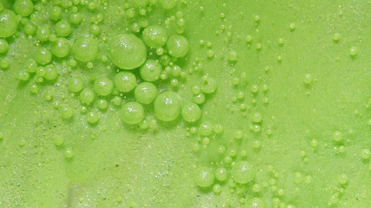 밝은 녹색 거품이 반이고 있습니다.