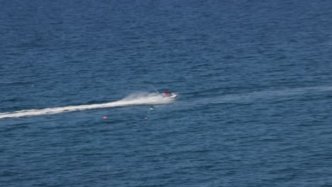 Hand-held-tracking-shot-of-a-jet-skier-racing-across-the-ocean-at-Newquay,-Cornwall