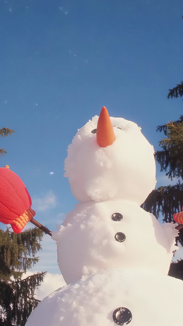 Vertical video: Tilting camera framing large three-tier snowman in yard, showing sky and mittens