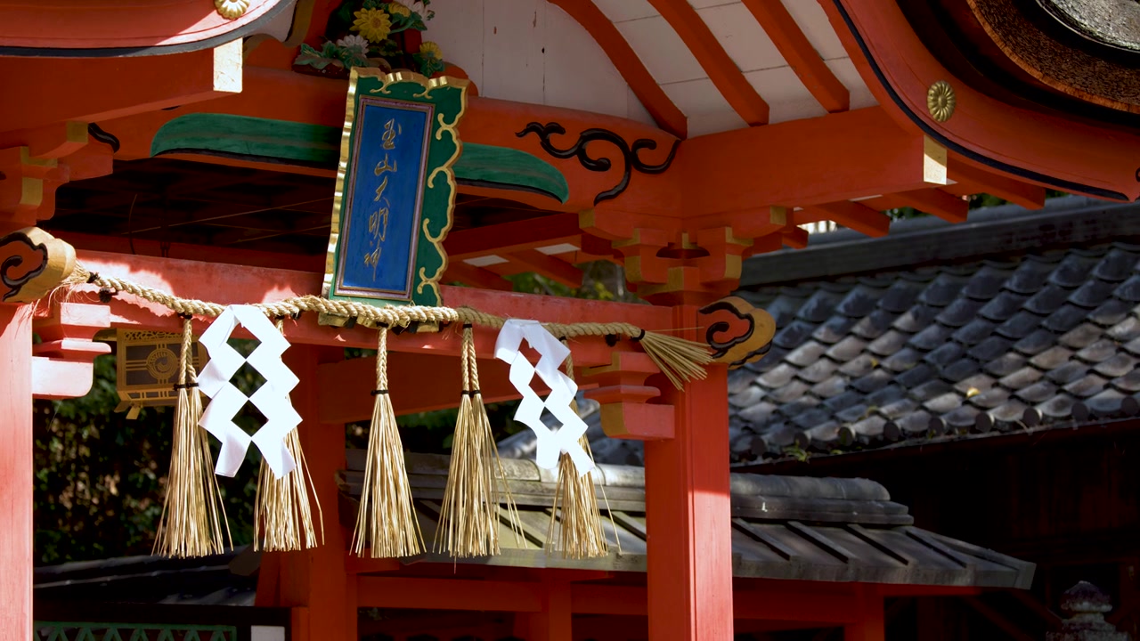 Close-up of a vermilion Shinto gate in Kyoto with traditional ritual rope and paper streamers