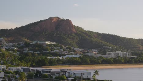 the stunning view at dawn of castle hill with the houses and hotels at its base overlooking the gorgeous sandy beach on a clear sky day