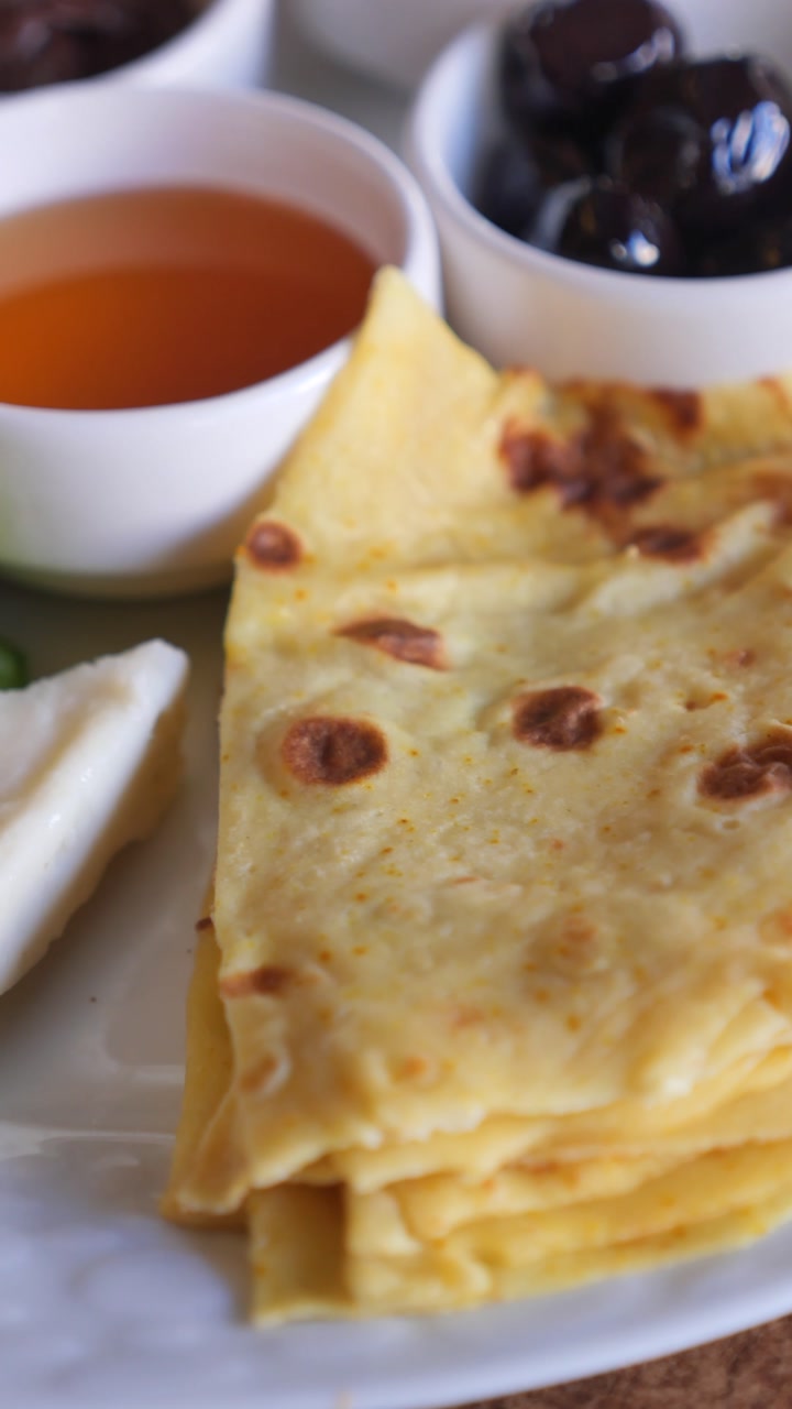 Close-up of a Traditional Breakfast Plate with Pancakes, Olives, Honey, and Cheese
