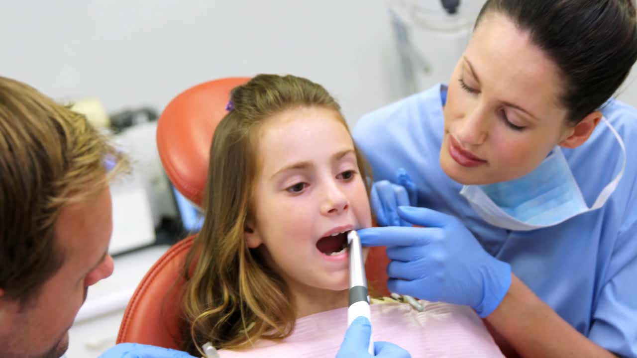 Dentist and nurse examining a young patient with tools