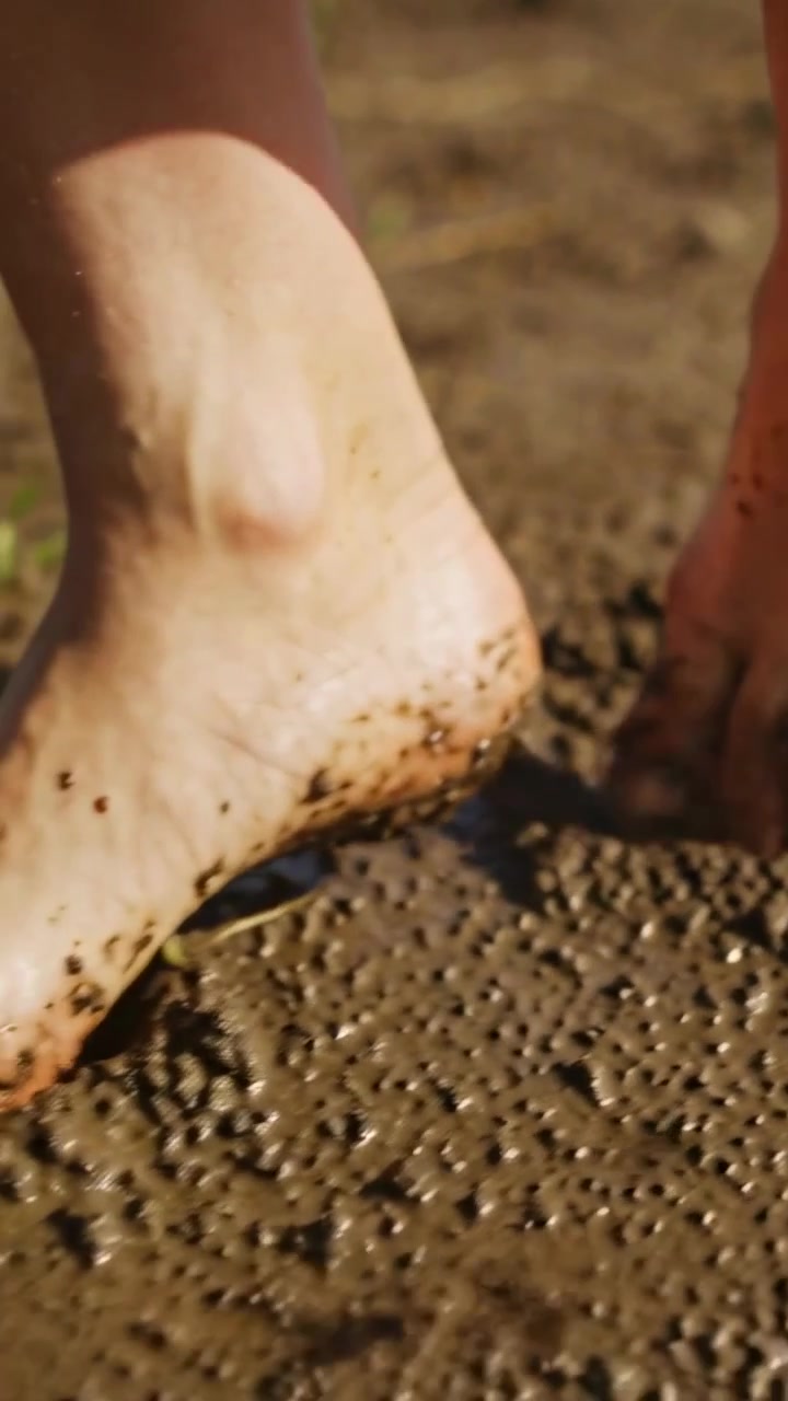 Video verticale: Spostando il peso, i piedi premono in una pozzanghera sulla riva, lasciando impronte bagnate.