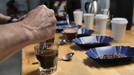 a master taster using coffee cupping to test quality, slow motion close up