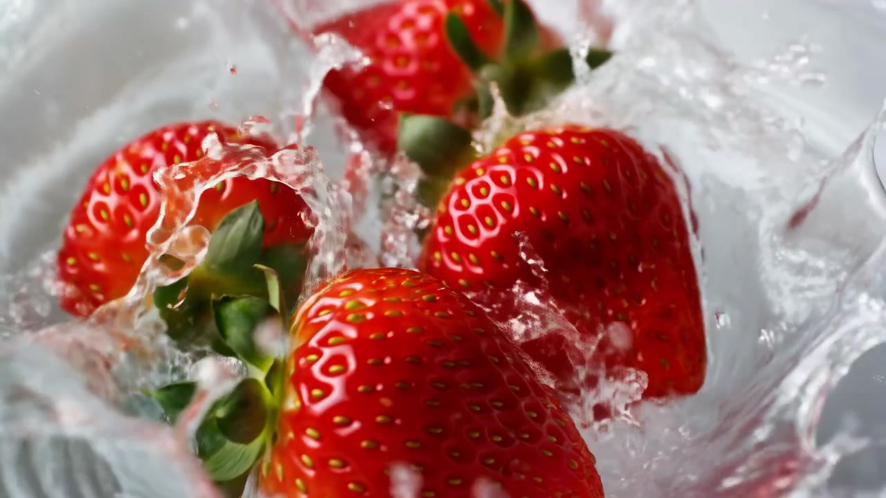 Fragole fresche che schizzano nell'acqua, bacche rosse vivaci che si scontrano con goccioline cristalline, movimento congelato ad alta velocità.