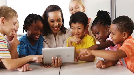 teacher teaching school kids on digital tablet in classroom