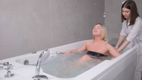a woman enjoying a hydromassage in a jacuzzi. a relaxed woman receives a hydromassage from a professional beautician in a spa center.