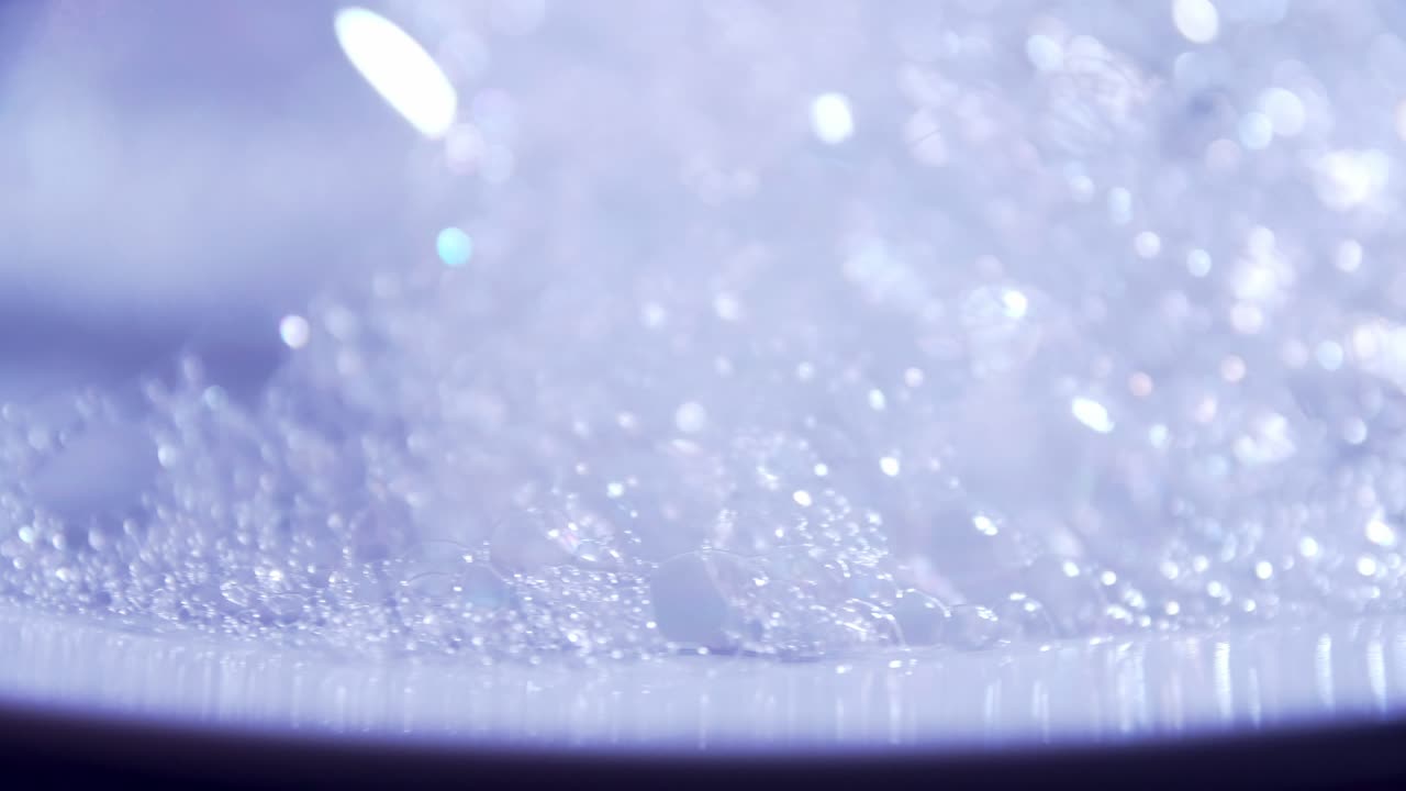 투명한 거품 거품이 흰 접시 주위를 돌고 있습니다.