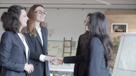 mujeres de negocios estrechando la mano en la sala de reuniones.