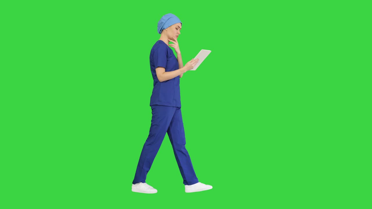 녹색 스크린, 크로마 키를 는 동안 터치 스크린 컴퓨터를 사용하는 스크럽을 입은 젊은 여성 의사 또는 간호사