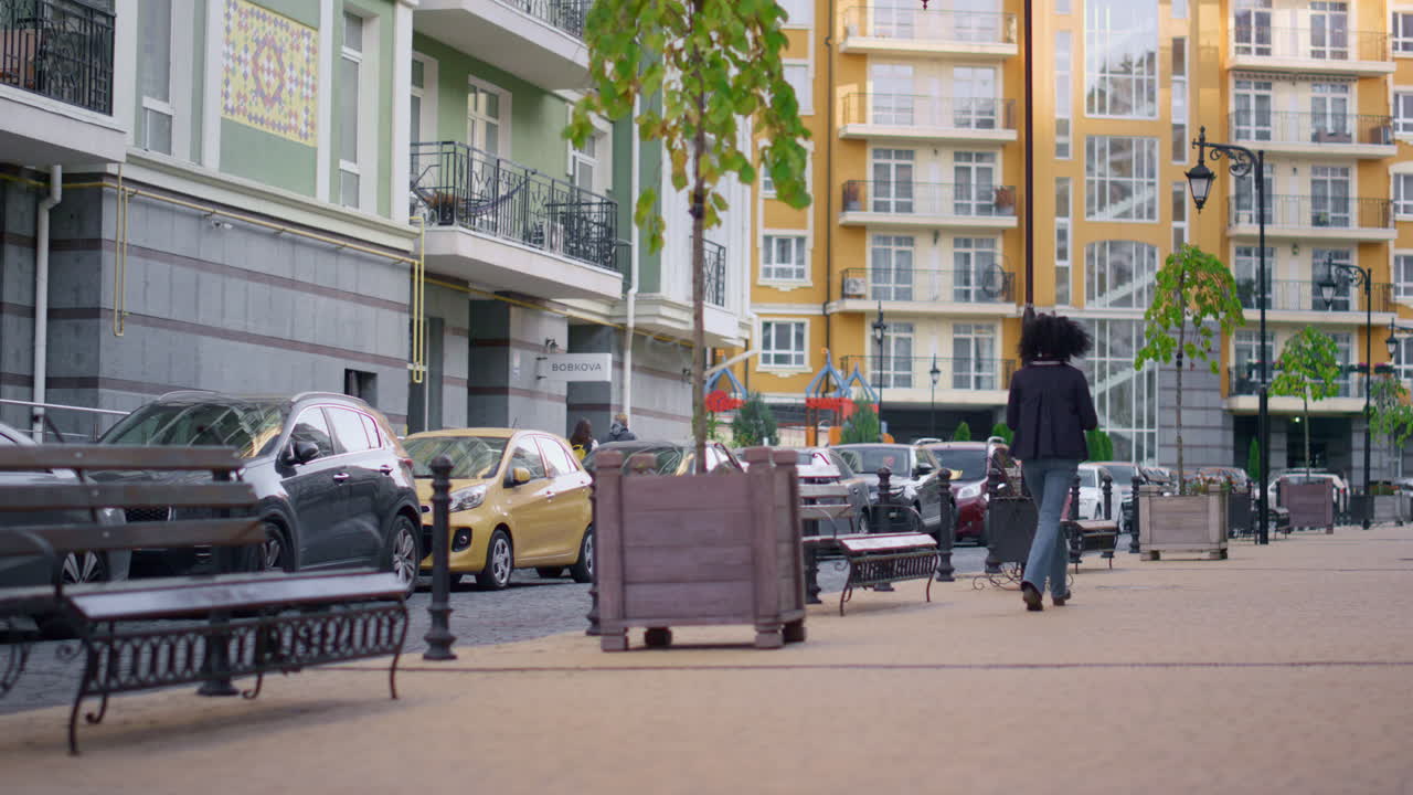 뒤쪽의 여자가 혼자 빈 거리를  ⁇ 고 있는 도시. 현대적인 주거 지역.