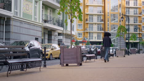 mujer de la parte trasera caminando por la ciudad calle vacía sola. zona residencial moderna.