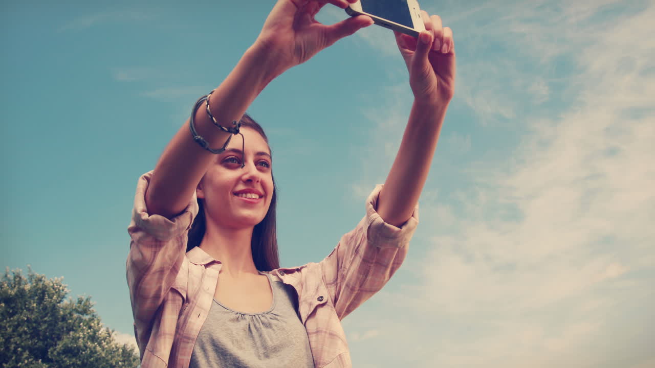 una morena bonita tomando una selfie en el parque.