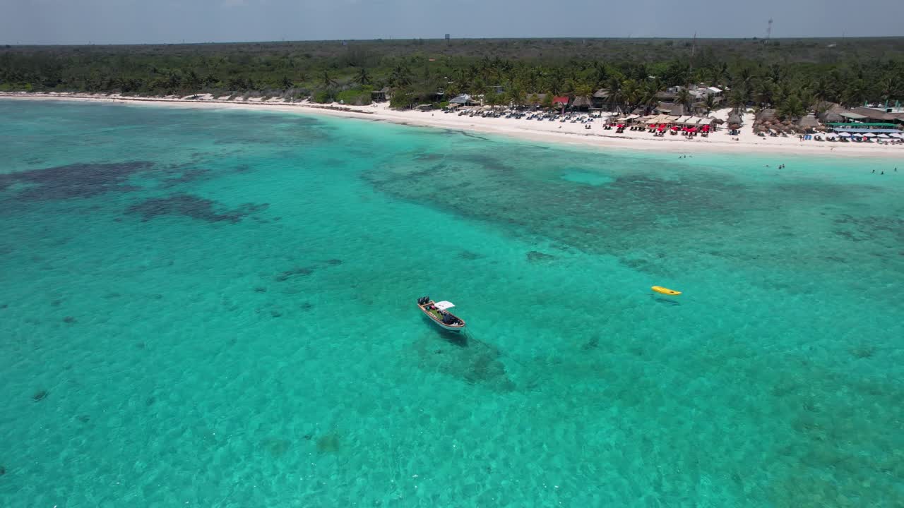 drone aéreo océano azul vibrante en el complejo de playa de méxico de tulum, barco y kayak en medio de cielos despejados