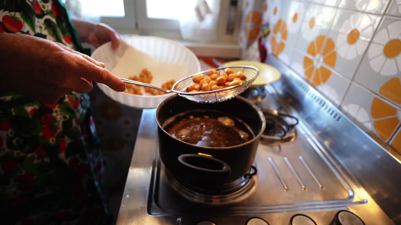 스키머로 튀긴 struffoli 패스트리 볼에서 끓는 기름을 빼냅니다.