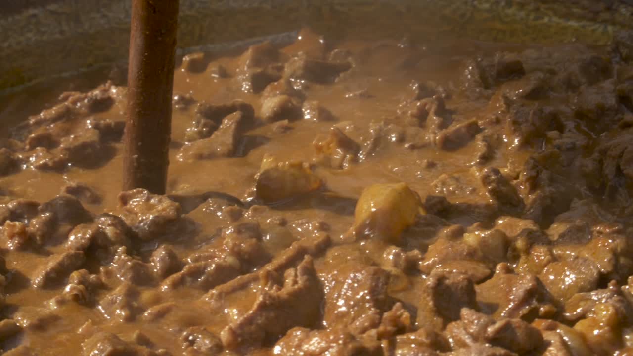 cocinar estofado de jabalí en un caldero al fuego - cámara lenta de 180 fps
