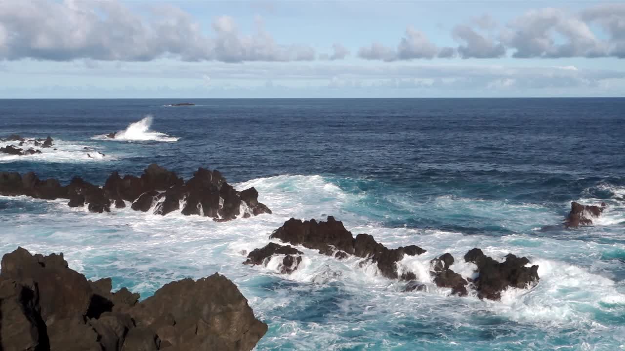 Onde che si infrangono sulla costa rocciosa in una giornata di sole.
