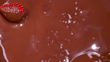 strawberry being dipped into melted chocolate