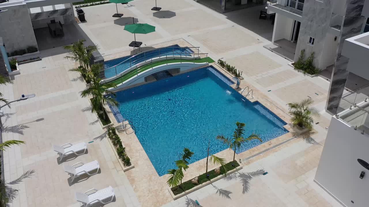Dronebillede af smuk, blå swimmingpool i landvilla