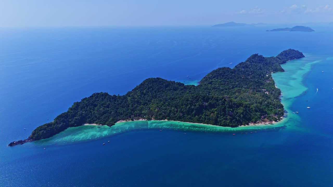 Aerial view of Koh Kradan, Thailand, showcasing the entire island with lush greenery, turquoise waters, and white sandy beaches. A stunning tropical paradise in the Andaman Sea in 4K.