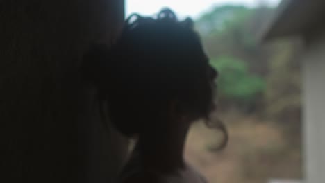 silhouette of a woman in soft focus gazing out from a dim, rustic setting