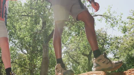 Low-section-of-diverse-couple-hiking-with-backpacks-in-park,-slow-motion