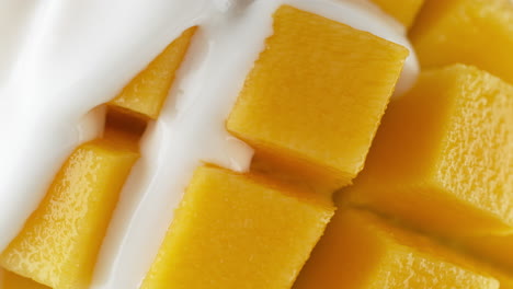 mango poured with yogurt - a thick liquid flows between the cubes of the fruit