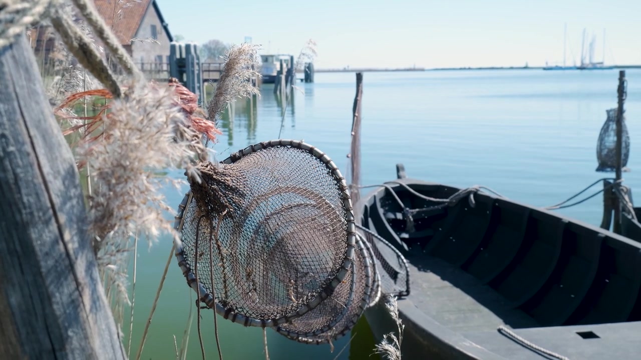 Reti da pesca tradizionali appese a una barca di legno in un porto tranquillo