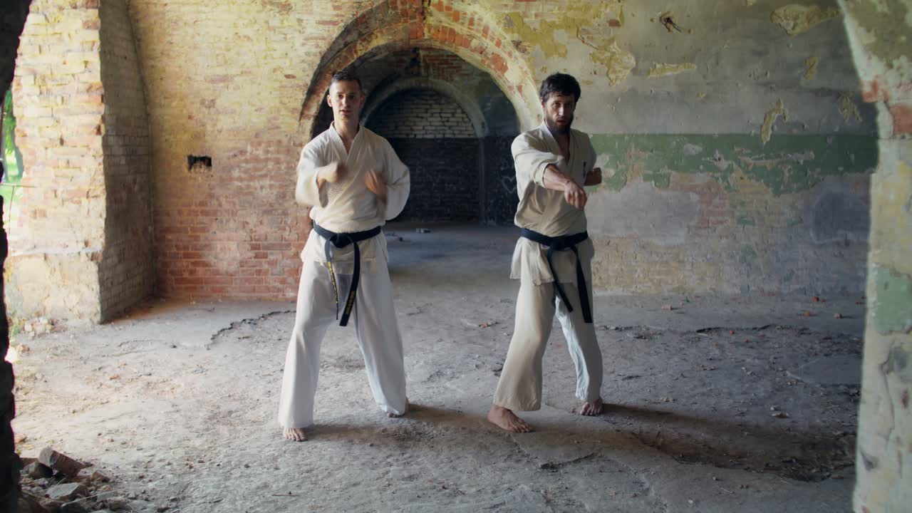 Terk edilmiş bir binada iki adam karate yapıyor.