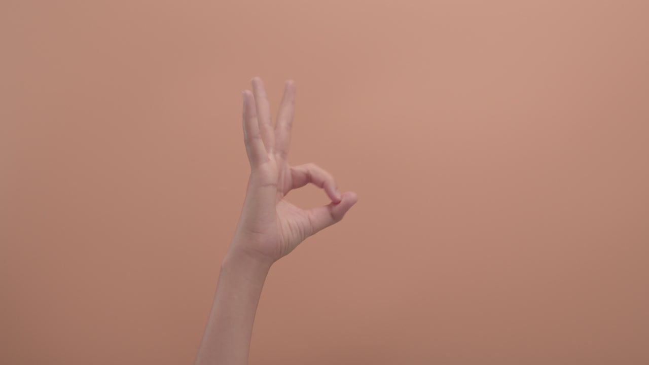 여성의 손의 클로즈업은 색의 배경으로 다는 의미의 모양을 만니다.