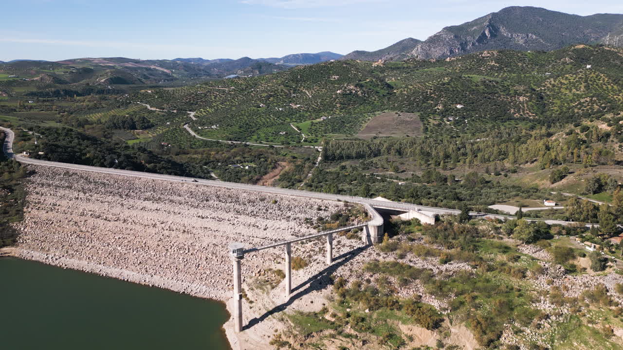 Drone over dam as cars drive past. The Zahara-El Gastor Reservoir