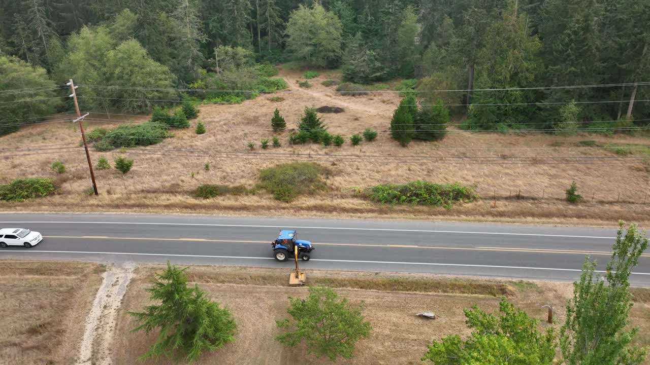 toma de drones estáticos de un tractor cortando las malas hierbas en las zanjas de un pequeño pueblo en américa