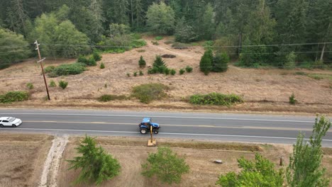 Toma-De-Drones-Estáticos-De-Un-Tractor-Cortando-Las-Malas-Hierbas-En-Las-Zanjas-De-Un-Pequeño-Pueblo-En-América