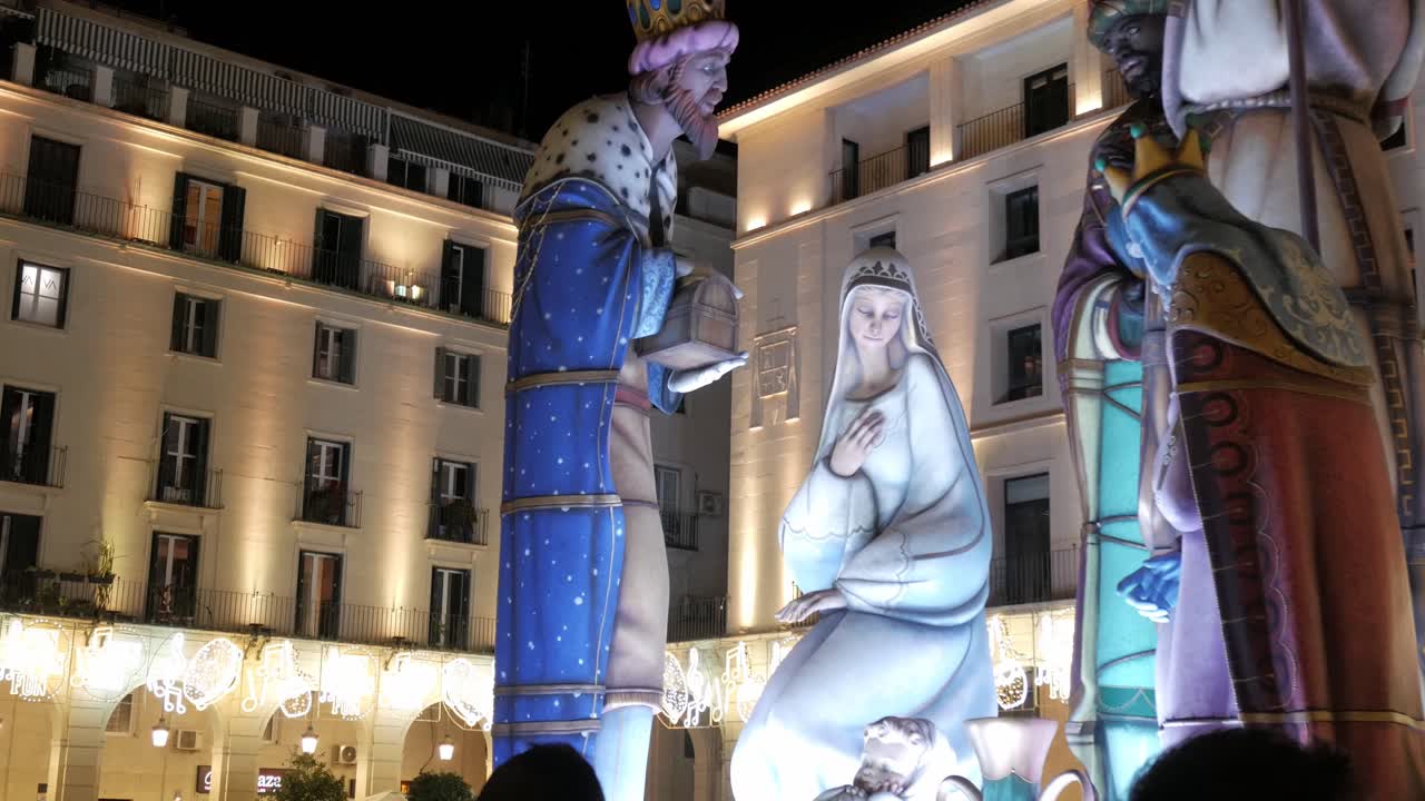 Giant Nativity figures in the city at night with lights in the buildings.The town hall of Alicante.