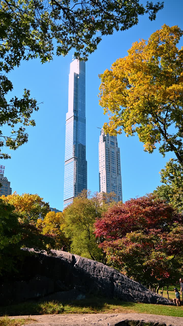New York, USA, 2 agosto 2025: Paesaggio autunnale di Central Park con grattacieli e fogliame colorato. Veduta soleggiata delle rocce di scisto di Manhattan e alberi con vivaci colori autunnali e alti edifici.