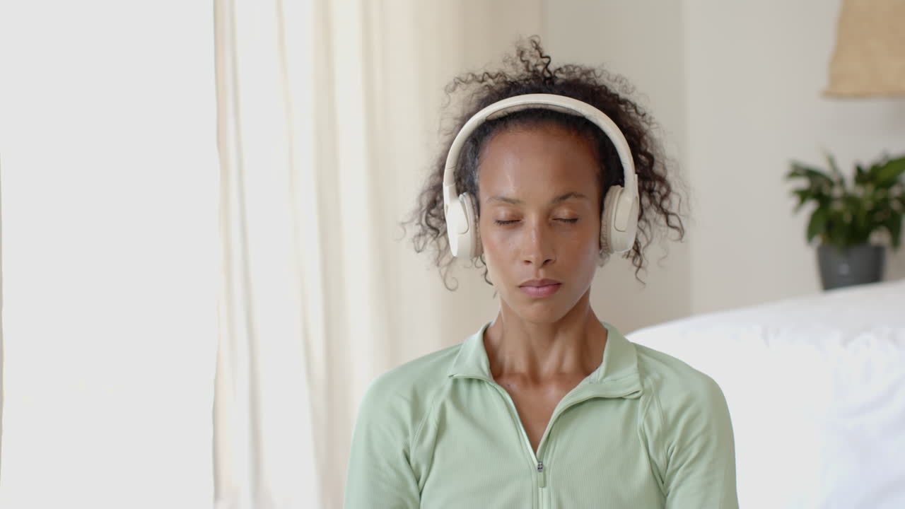 woman meditating with headphones at home, focusing on relaxation