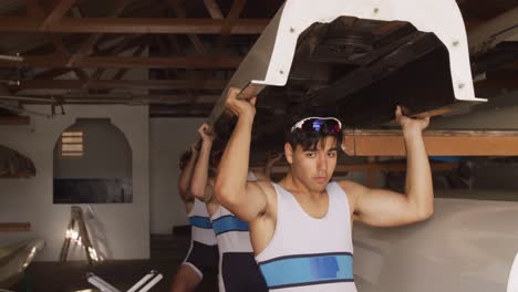 equipo de remadores masculinos llevando el bote por encima de su cabeza