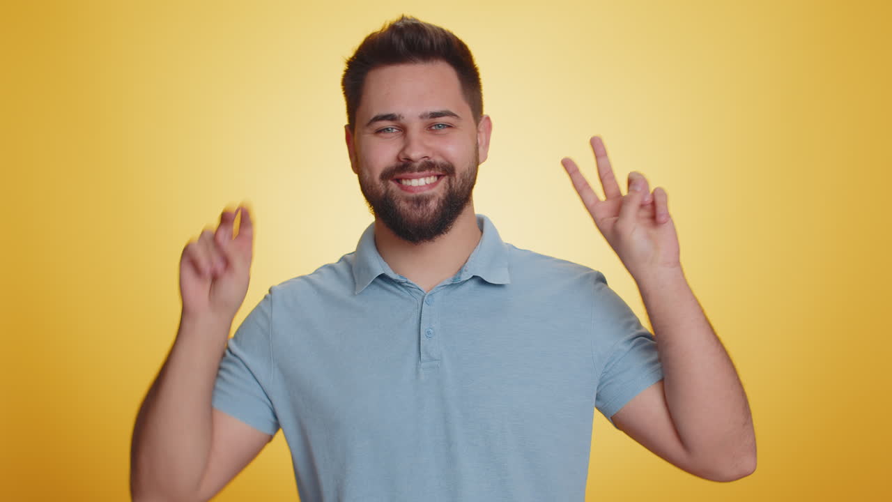 Young caucasian man showing victory sign hoping for success and win doing peace gesture smiling