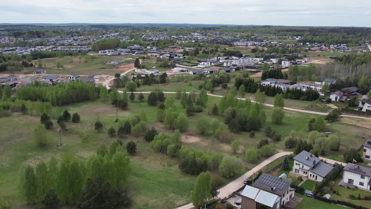 Forward drone shot over greenery toward lowrise homes in Zujūnai, Vilnius