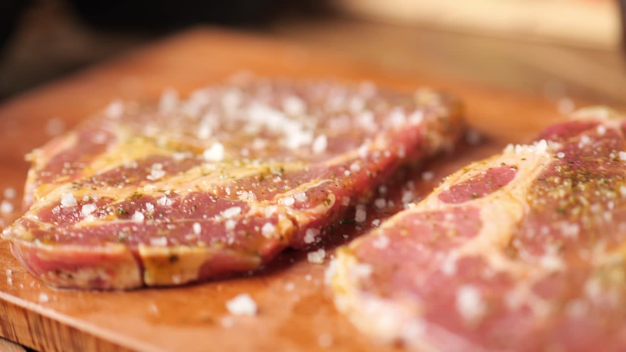 handheld tracking shot over the grill table with steak, peppers and salt
