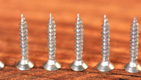 steel screws on wooden table. screw production, heap of metal details, close up shot