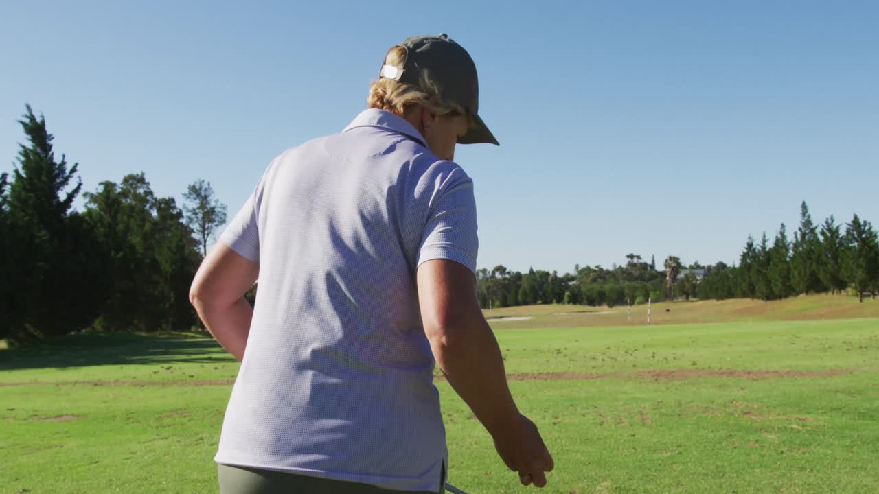 골프 공을 잡기 위해 잔디 위에 놓고 있는 백인 고위 여성