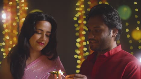 portrait of young couple celebrating festival of diwali lighting diya oil lamp