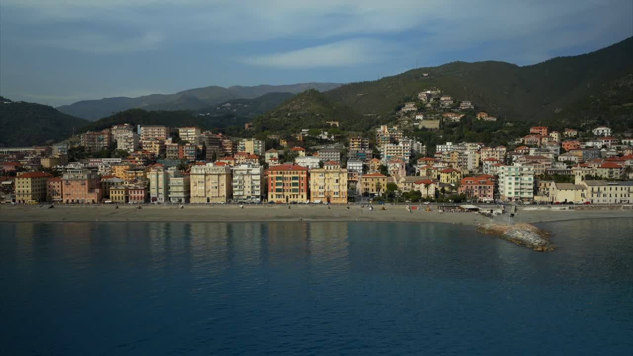 Overhead drone shot of the idyllic seaside village of Varazze with calm, turquoise ocean waters and busy metropolitan area, and buildings