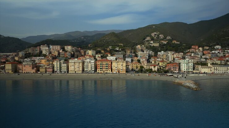 Overhead drone shot of the idyllic seaside village of Varazze with calm, turquoise ocean waters and busy metropolitan area, and buildings