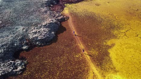 people walking on abstract colored red yellow and grey hydrothermal field at hottest place on earth