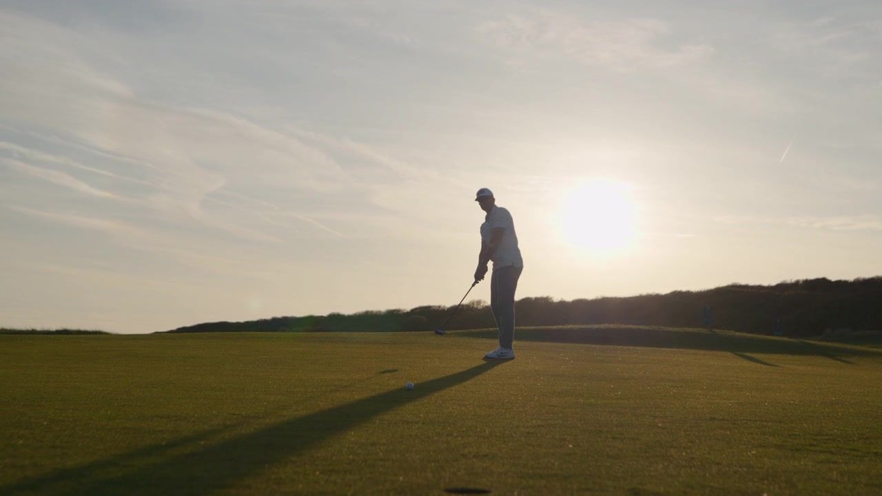 Golfista uomo che putta la pallina da golf sul green e sbaglia, carrellata all'indietro che rivela la buca