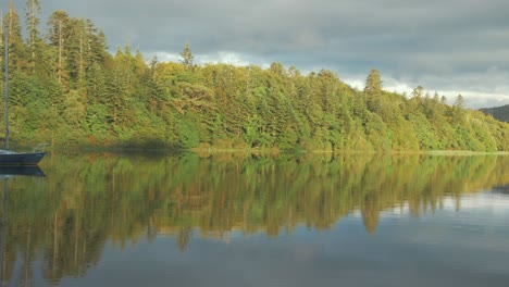 incredible dream like view of sailboat moored looking out to vibrant wilderness lake view