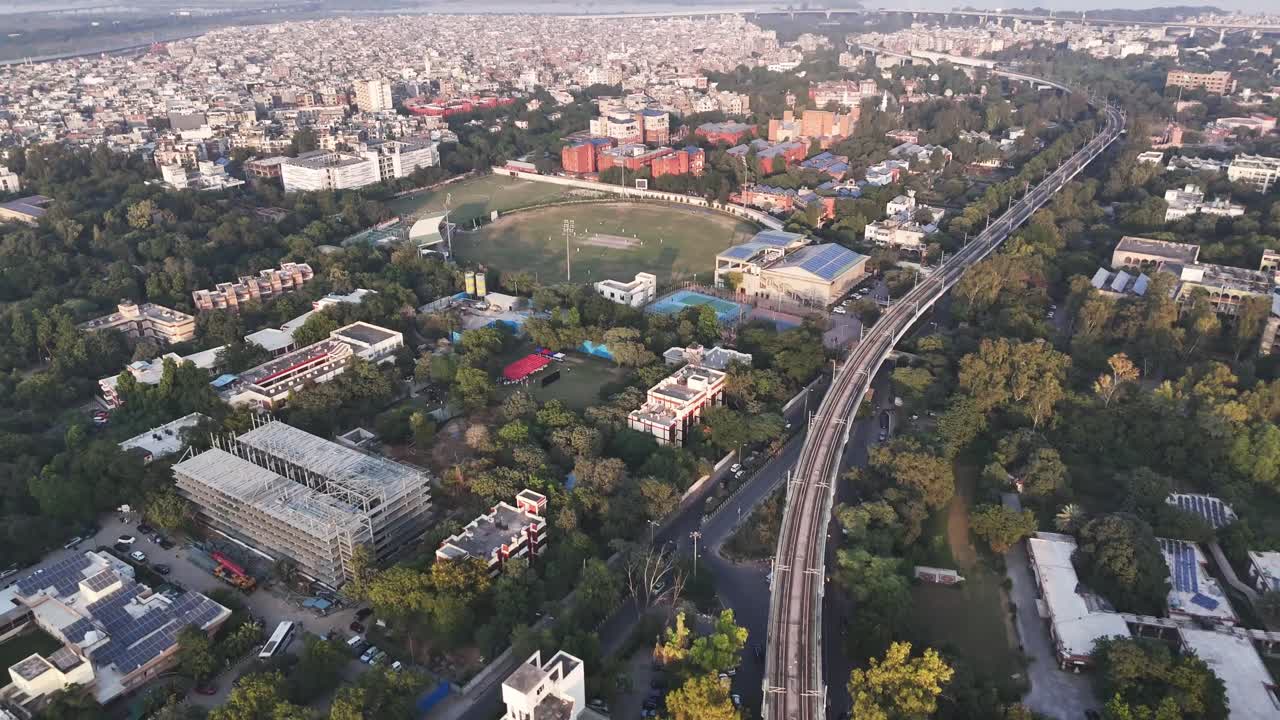 Ripresa aerea di un campo da cricket a South Delhi, incorniciato da alberi e quartieri, che mette in evidenza l'amore della città per il cricket sullo sfondo di un denso paesaggio urbano